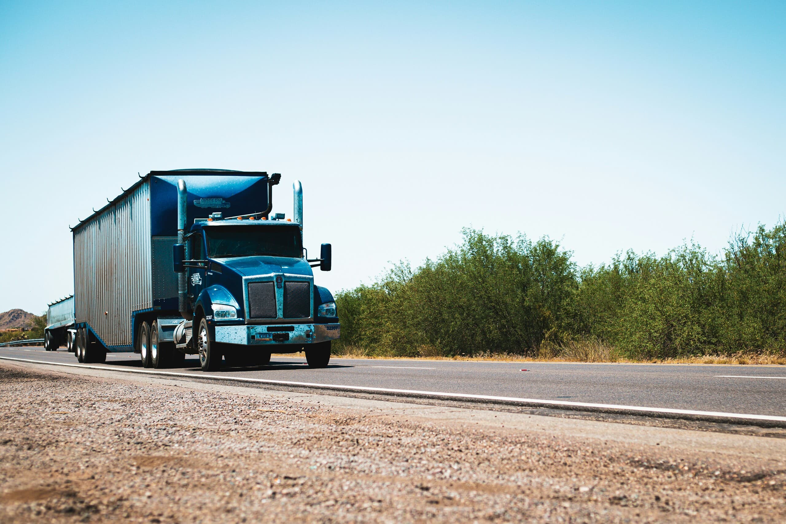 A semi-truck drives in the desert
